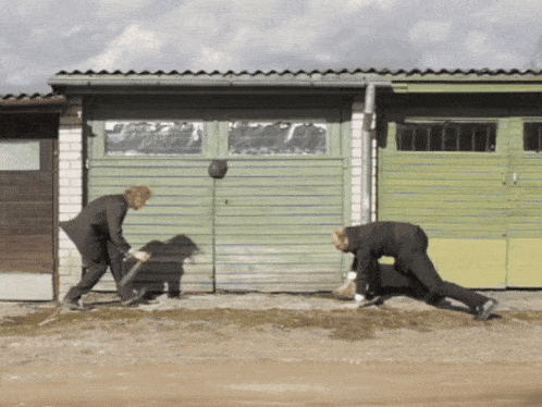 a couple of men standing in front of a green garage