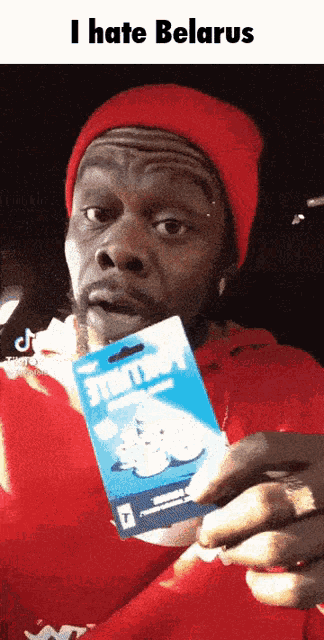 a man in a red hat is holding a card that says ' i hate belarus ' on it