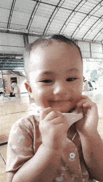 a baby is making a funny face while holding a piece of chicken