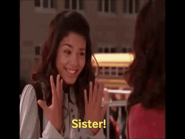 a woman is smiling while talking to another woman and the words sister are on the screen .