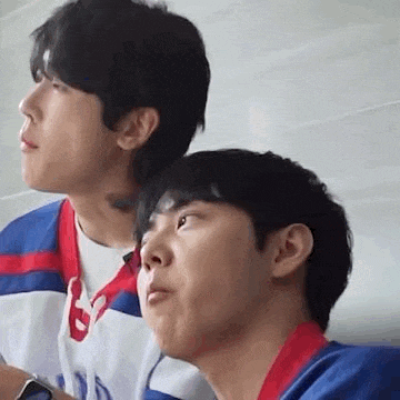 two young men are sitting next to each other in a classroom .
