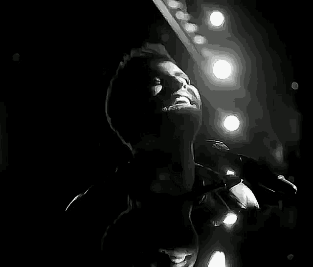a man singing into a microphone in a black and white photo