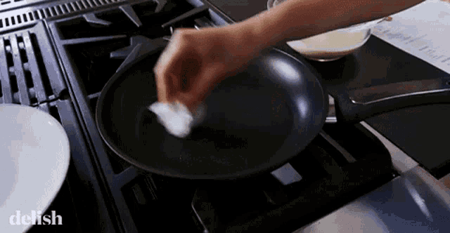 a person is cleaning a frying pan on a stove with the word delish visible in the corner