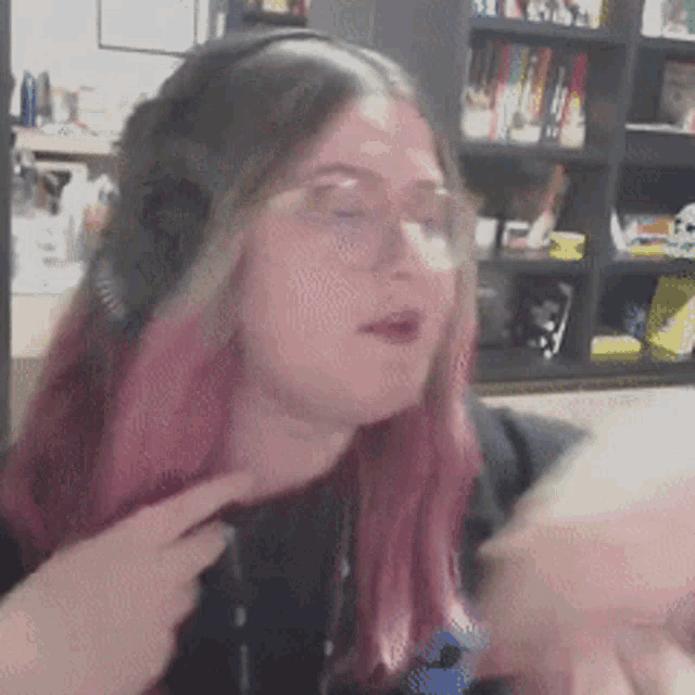 a woman with pink hair and glasses is wearing headphones and a black shirt
