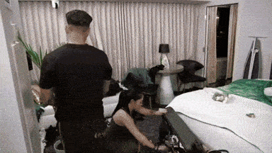 a man and a woman are standing in a room with a bed .