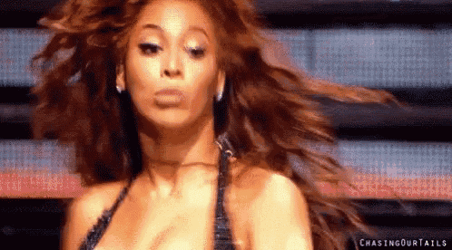 a woman with long hair is making a funny face while dancing on a stage .