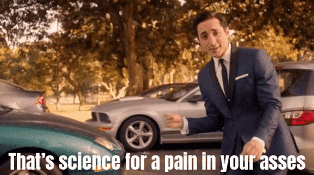 a man in a suit and tie is standing in front of a row of cars and says that 's science
