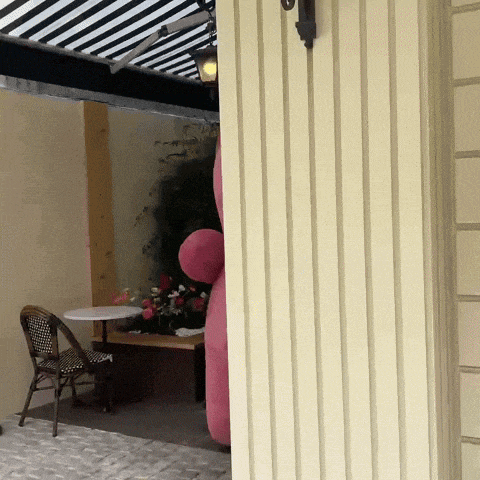 a pink balloon is hanging on a wall next to a table and chairs