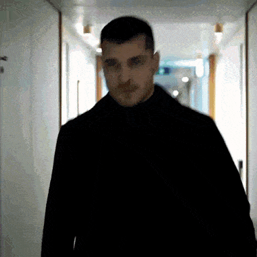 a blurry picture of a man in a black coat walking down a hallway