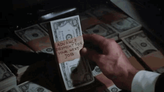 a person is holding a stack of 100 dollar bills with a note taped to it that says advance payment for your next job