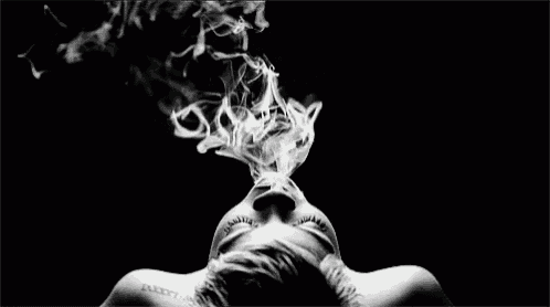 a black and white photo of a woman smoking a cigarette .