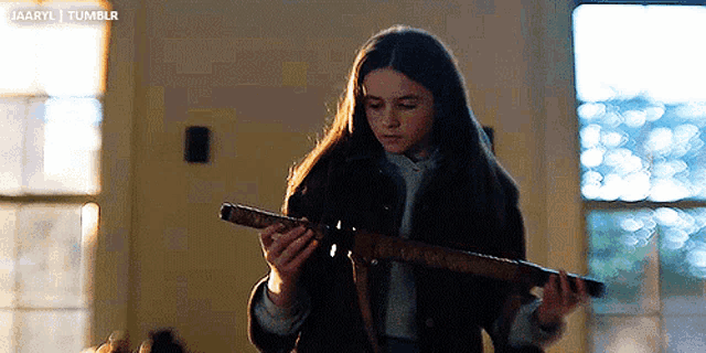 a young girl is holding a telescope in a living room .