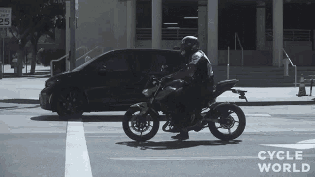 a person riding a motorcycle on a street with the words cycle world on the bottom