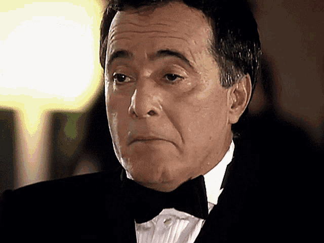 a man in a tuxedo with a bow tie looks serious