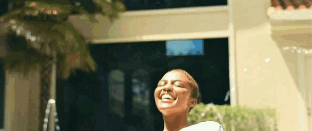 a woman is laughing with her eyes closed in front of a house