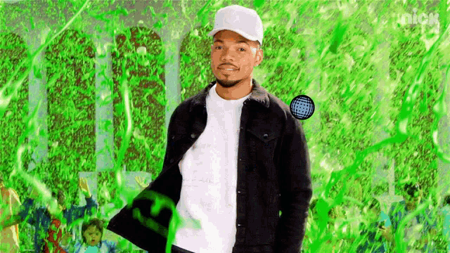 a man in a black jacket and white hat is standing in front of a green background covered in green slime .