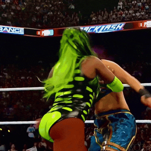 a woman with green hair is wrestling another woman in front of a sign that says ' smack '