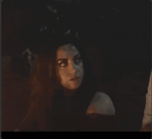 a woman with long red hair is looking down in the dark