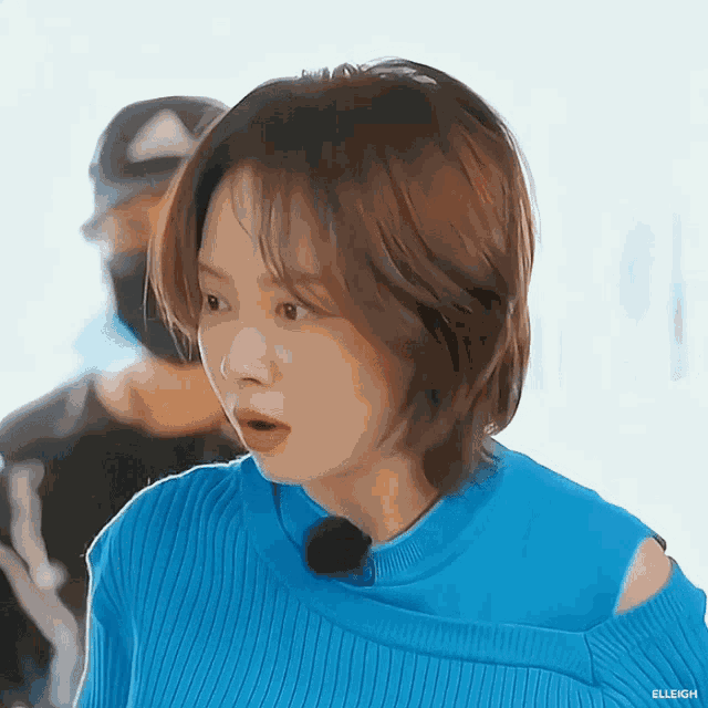 a woman wearing a blue off the shoulder sweater with elleigh written on the bottom