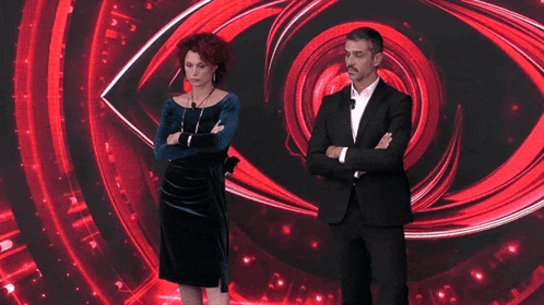 a man and woman are standing in front of a large red eye
