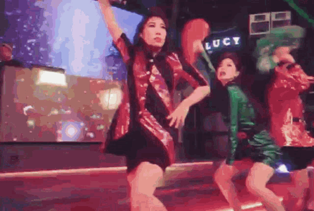 a group of women are dancing in front of a sign that says lucy .