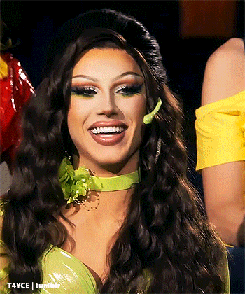a drag queen wearing a green dress and a green choker is smiling .
