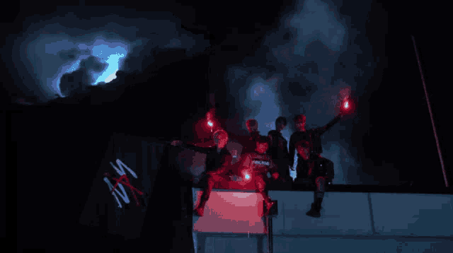 a group of people holding red flares in front of a sign that says ' ns ' on it