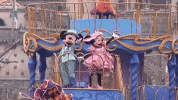 mickey mouse and minnie mouse are riding on a float in a parade