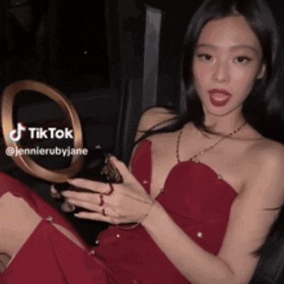 a woman in a red dress is sitting in the back seat of a car holding a cell phone .