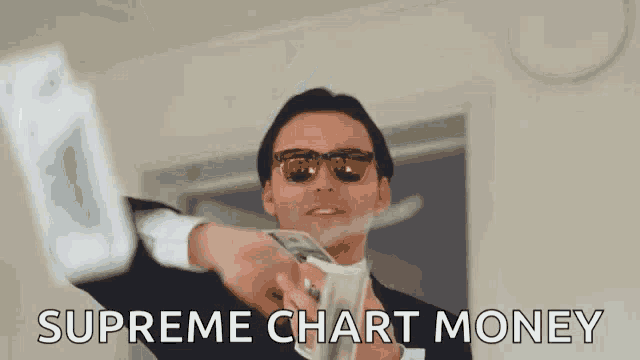 a man in a suit and sunglasses is holding a bunch of money and says `` supreme chart money '' .