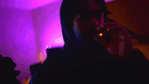 a man smoking a cigarette with a purple light behind him