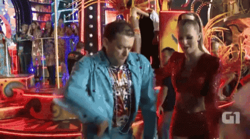 a man in a blue jacket is dancing with a woman in a red dress behind him .