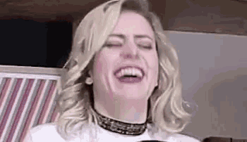 a woman with blonde hair is laughing with her eyes closed .