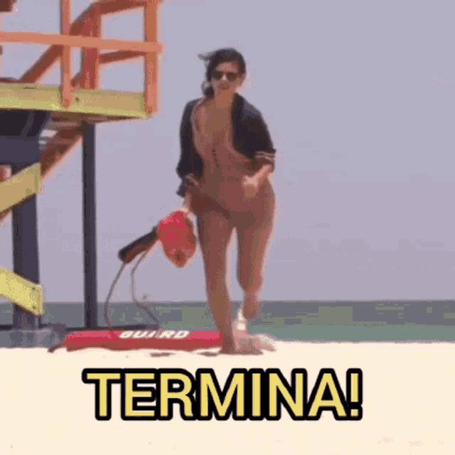 a woman in a bathing suit is running on a beach with the word termina written on the sand