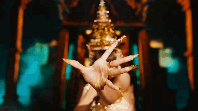 a woman with long nails is wearing a gold crown on her head