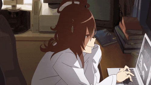 a woman sitting at a desk using a laptop with a stack of books in the background