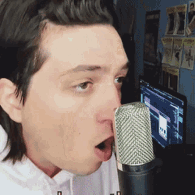 a man is singing into a microphone in front of a computer screen