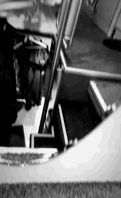 a black and white photo of a person walking down a set of stairs .