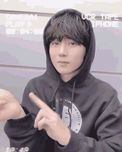 a young man wearing a black hoodie is pointing his finger