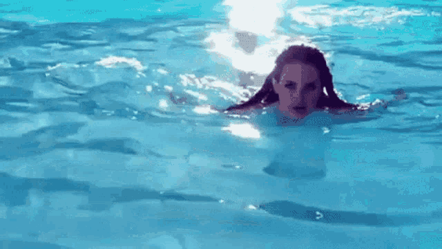 a woman is swimming in a pool with her hair visible .