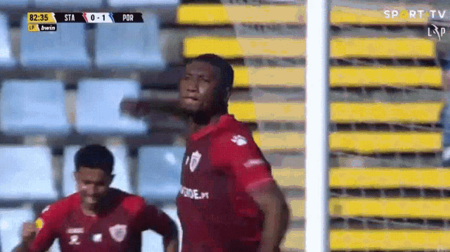 a soccer player in a red shirt is standing in front of a goal .