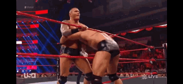 two men are wrestling in a wrestling ring with a referee watching .
