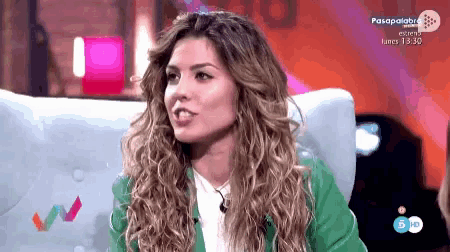 a woman in a green jacket is sitting in a chair on a television show called pasapalabra