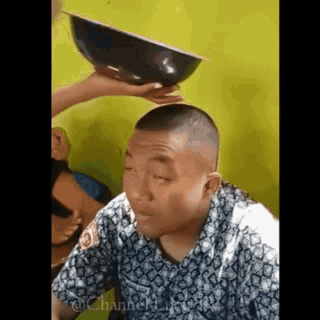 a man with a bowl on his head is making a funny face