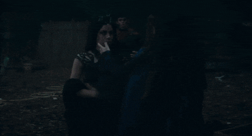 two women are kissing in a dark room and one of them is wearing a blue dress