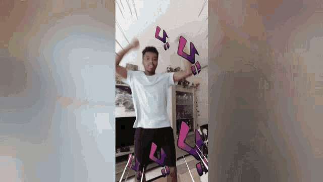 a man in a white shirt is dancing in a room with purple letters flying around him