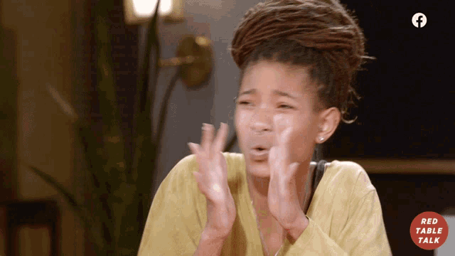 a woman with dreadlocks is clapping in front of a facebook logo