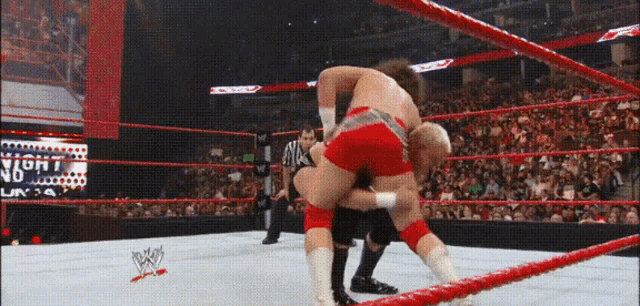 two men are wrestling in a wrestling ring with a sign that says night on it