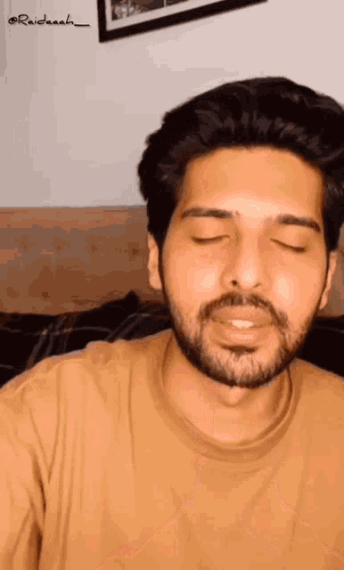 a man with a beard is wearing a brown shirt