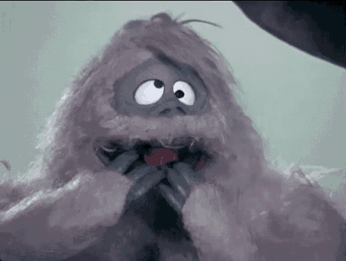 a stuffed animal with big eyes and a red tongue is eating a red apple .